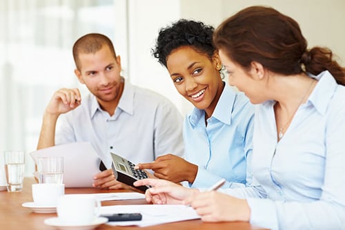 Woman talking with coworkers while holding calculator