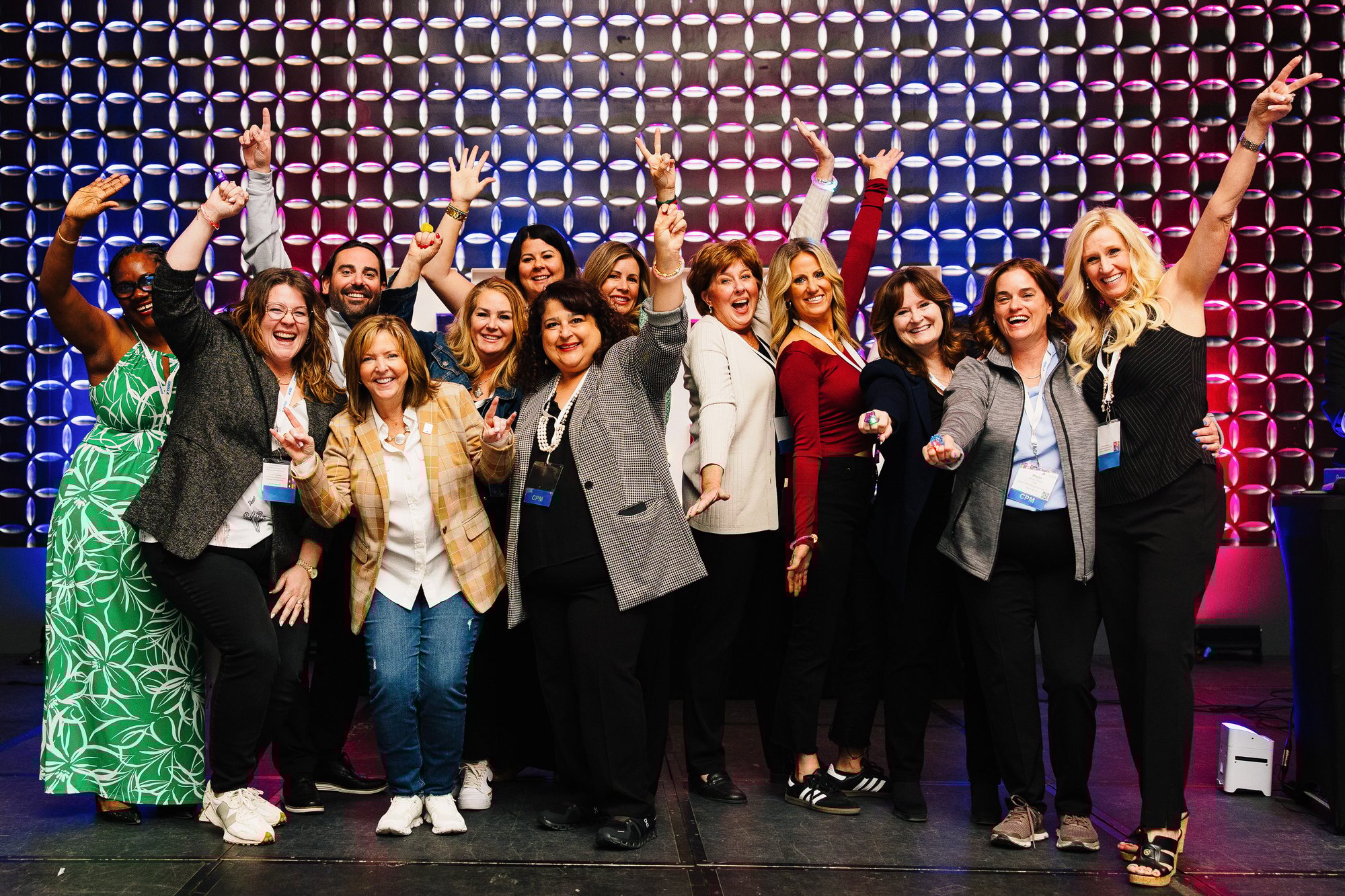 Group standing on stage smiling with hands raised at PropertyCon